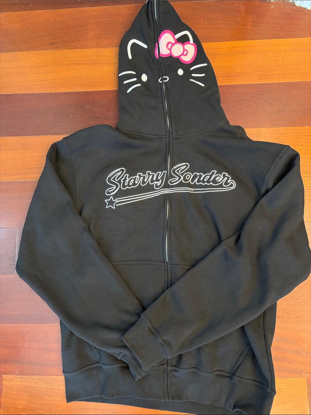 Starry Sonder Black Zip Hoodie with Hello Kitty details.